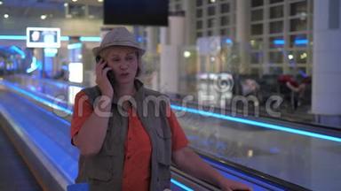 一个女人在机场坐着一台移动的自动扶梯，在打电话。